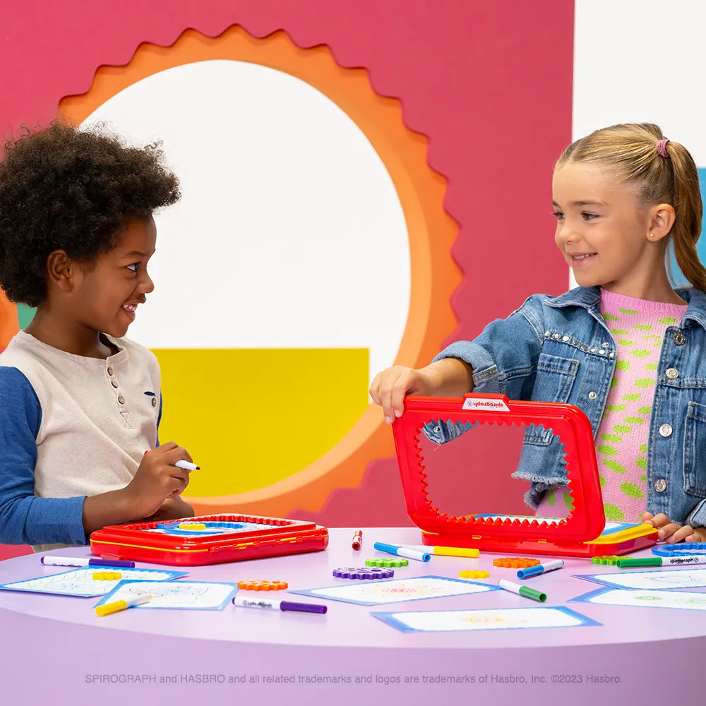 Two children drawing spiral designs with Spirograph Jr.
